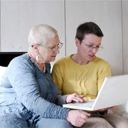 Older woman and younger woman looking together at laptop.